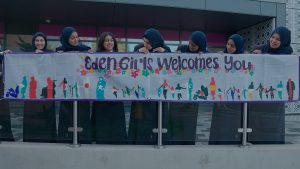 Students at Eden Girls' School holding up a banner saying 'Eden Girls' School welcomes you'