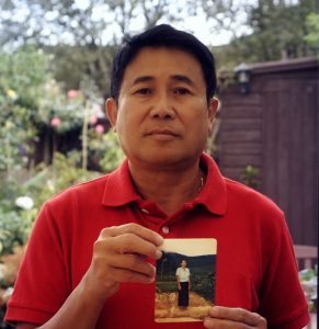 Photo of Sokphal holding a photo of his family