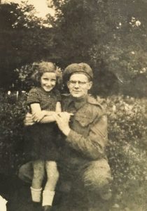 An old photo of Yvonne standing with her father, who is crouched down