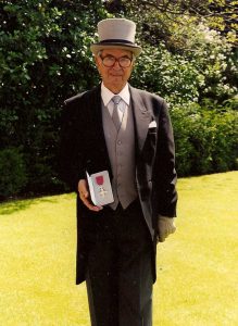 Henry Wuga dressed in a top hat and tails, holding his medal